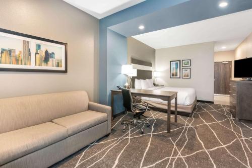 a hotel room with a couch and a desk and a bed at La Quinta Inn and Suites by Wyndham Houston Spring South in Spring