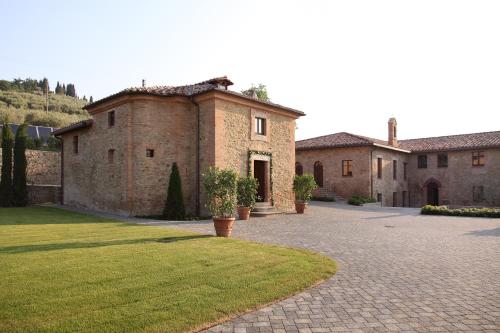a large brick building with a courtyard in front of it at Borgo Dei Conti Resort Relais & Chateaux in Monte Petriolo