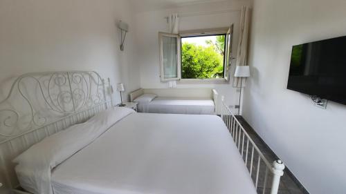 a white bedroom with a bed and a window at villa Bismarkia in Siracusa