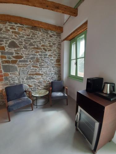 a living room with two chairs and a tv at Dvor Vipolže in Dobrovo