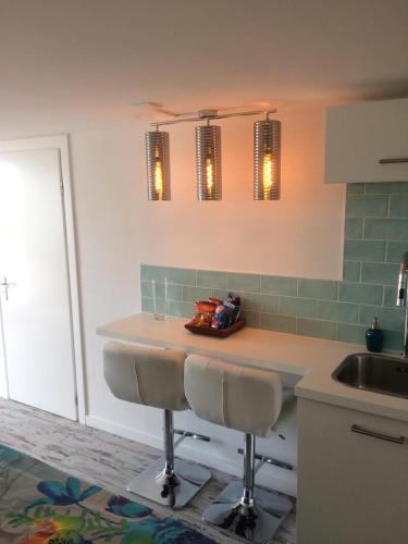 a kitchen with a counter with two stools and a sink at little ibiza in Zandvoort