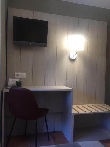 a desk with a chair and a television on a wall at Hotel Rural Valle San Emiliano in San Emiliano