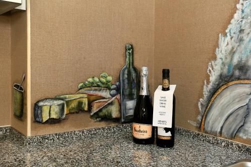 two bottles of wine sitting next to a painting at HENRI'S APARTMENTS - Pátio do Convento in Lagos