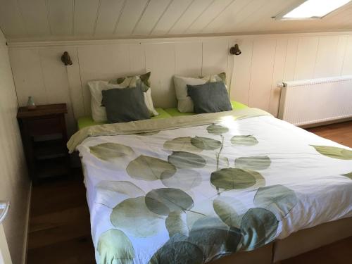 ein Schlafzimmer mit einem Bett mit einer Decke mit Blättern darauf in der Unterkunft B&B HemeltjeLief in Hemelum