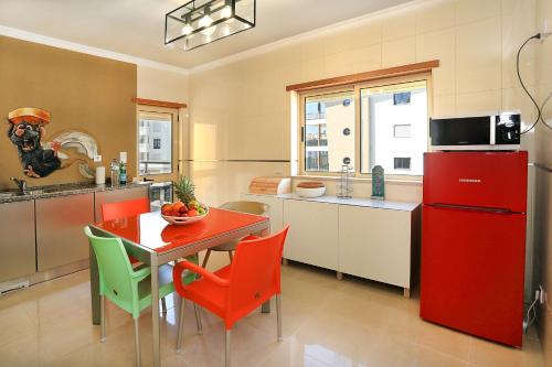 uma cozinha com um frigorífico vermelho e uma mesa com cadeiras em HENRI'S APARTMENTS - Pátio do Convento em Lagos