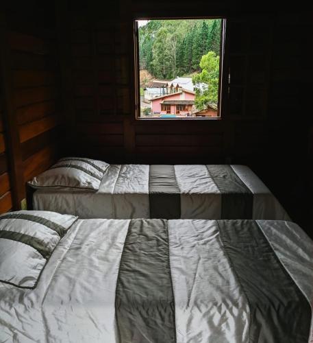 two beds in a room with a window at Pousada Aracê in Pedra Azul