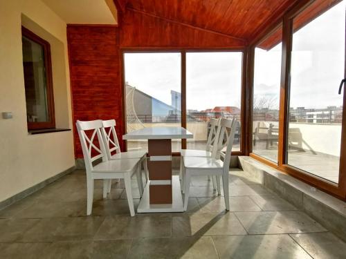 a table and chairs in a room with windows at VIP Apartment-Brilliant Apartments in Constanţa