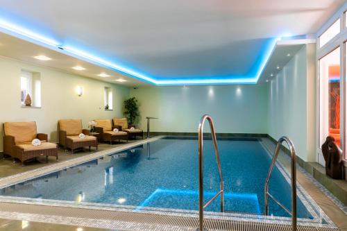 una piscina in un hotel con sedie e un divano di Hotel & Restaurant Villa Ulmenhof a Bredstedt