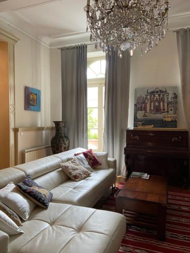 ein Wohnzimmer mit einem weißen Sofa und einem Kronleuchter in der Unterkunft Le Gîte du Château in Auriac-sur-Vendinelle
