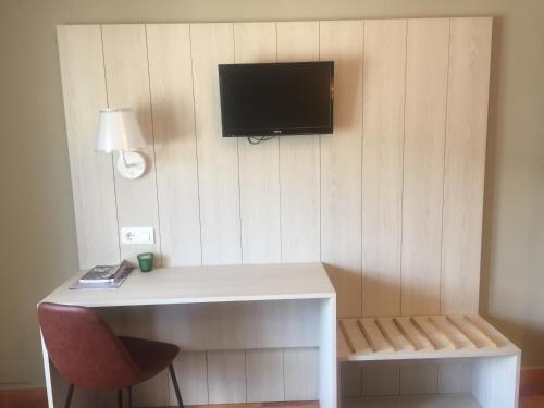 a room with a desk and a tv on a wall at Hotel Rural Valle San Emiliano in San Emiliano