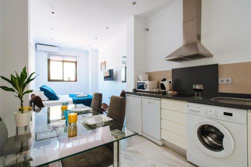 a kitchen with a washing machine and a dining room at Hostly Plaza de Armas Lightfull loft-Center-Parking op-CLess in Seville