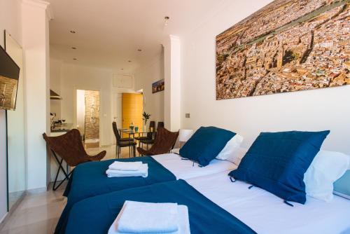 two beds in a room with blue pillows at Hostly Plaza de Armas Lightfull loft-Center-Parking op-CLess in Seville