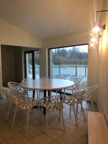 a dining room with a table and chairs and a window at Sodyba Pelėdų medus in Vainekoniai