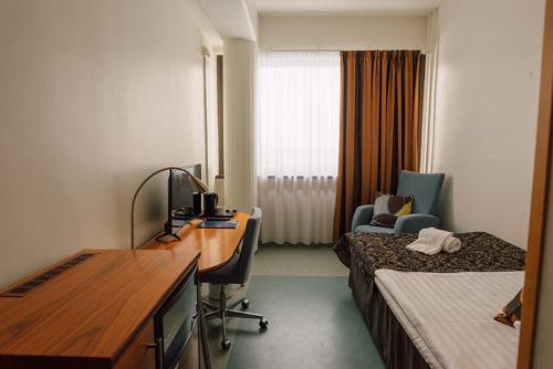 a hotel room with a desk and a bedroom at Hotelliravintola Kumpu in Outokumpu
