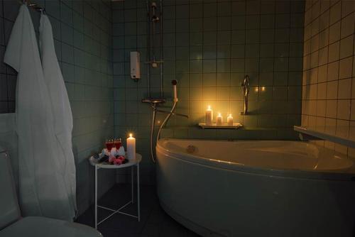 a bathroom with a tub and candles and a sink at Hotelliravintola Kumpu in Outokumpu