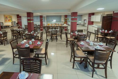 a restaurant with wooden tables and chairs and a kitchen at SJ Tour - San Juan Foz do Iguaçu in Foz do Iguaçu