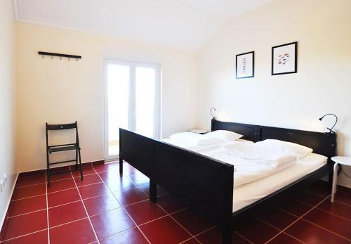a bedroom with a black bed and a chair at Casa Sardinha - Praia e Piscina - T2 (6 pessoas) in Ferrel