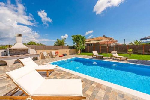 a swimming pool in a backyard with white furniture at Pothos Villas in Zakynthos Town