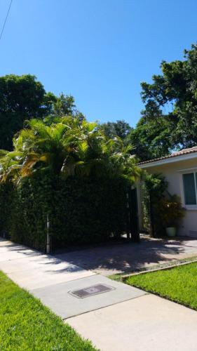 a house with a hedge next to a sidewalk at LUXURY Guayabita's House in Miami