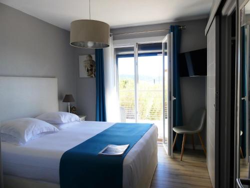um quarto de hotel com uma cama e uma porta de vidro deslizante em Hôtel de la Vierge Noire em Sainte-Maxime