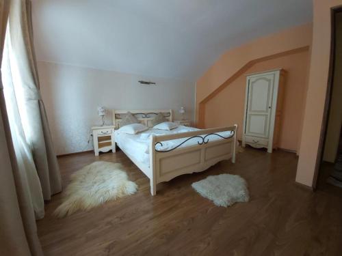 Vila Piscul Ursului في بريدال: غرفة نوم بسرير ابيض وارضية خشبية