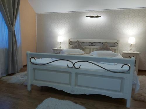 a bedroom with a white bed with two lamps on it at Vila Piscul Ursului in Predeal