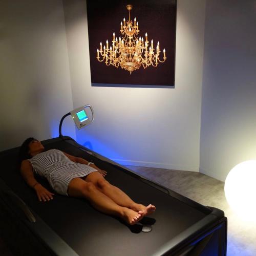 a woman laying on a bed under a chandelier at Altos Hotel & Spa in Avranches