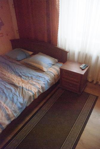 a bed with a night stand next to a window at Eha Suija Home Accommodation in Tartu