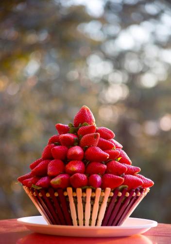 a cupcake with strawberries on a plate on a table at Shivsagar Resort & Spa in Mahabaleshwar