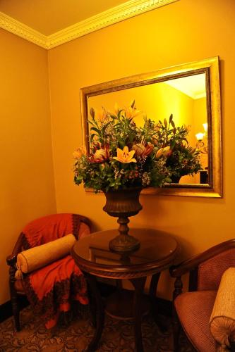 a vase of flowers on a table in front of a mirror at Anta Boga Hotel in Bloemfontein