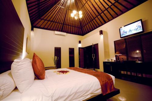 a bedroom with a large white bed with a flat screen tv at Askara Villa in Canggu