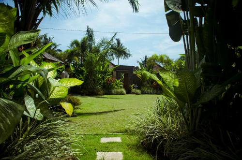 a garden with grass and plants and a house at Askara Villa in Canggu