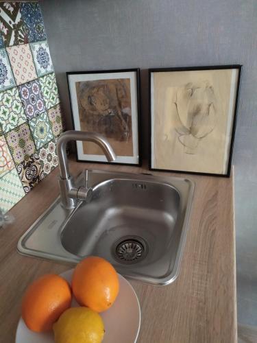 a sink with three paintings and oranges on a counter at Апартаменти Світлий Ранок та Затишний Вечір in Rivne