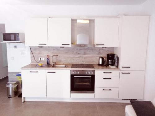 una cocina blanca con armarios blancos y fregadero en Apartment OG en Oststeinbek