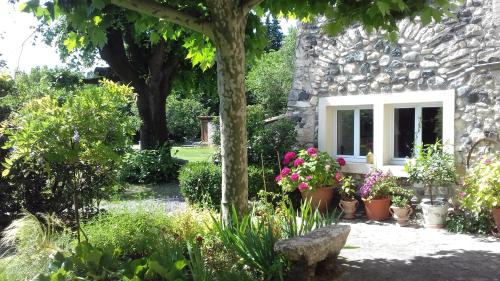 un jardin avec des plantes en pot devant un bâtiment en pierre dans l'établissement Malarias 1, à Rochemaure