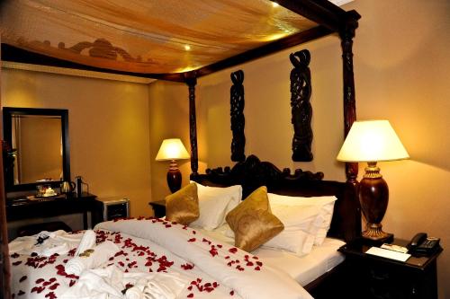 a bedroom with a large bed with red flowers on it at Anta Boga Hotel in Bloemfontein