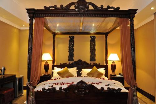 ein Schlafzimmer mit einem großen Himmelbett mit Kissen aus Holz in der Unterkunft Anta Boga Hotel in Bloemfontein