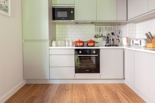 a white kitchen with white cabinets and an oven at Castle View Luxury 1 Bed Apartment in Edinburgh