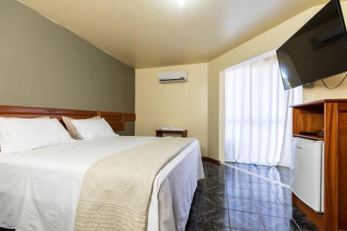 a bedroom with a bed and a flat screen tv at Canzi Cataratas Hotel in Foz do Iguaçu