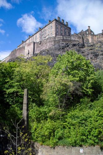 a castle on top of a hill with trees at Castle View Luxury 1 Bed Apartment in Edinburgh