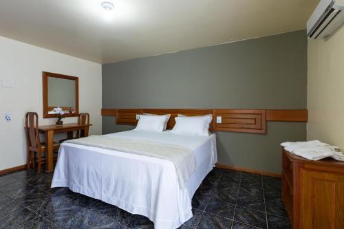 a bedroom with a large white bed and a table at Canzi Cataratas Hotel in Foz do Iguaçu
