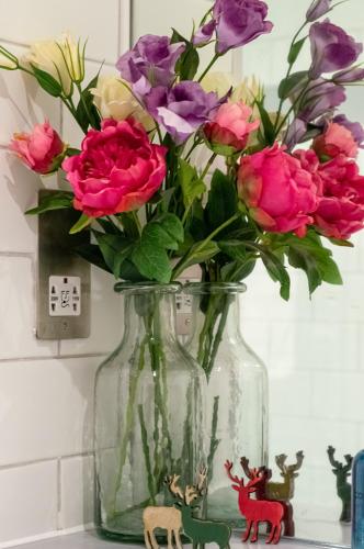 a glass vase filled with flowers on a shelf at Castle View Luxury 1 Bed Apartment in Edinburgh