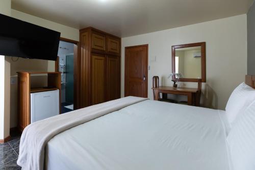 a bedroom with a large white bed and a television at Canzi Cataratas Hotel in Foz do Iguaçu