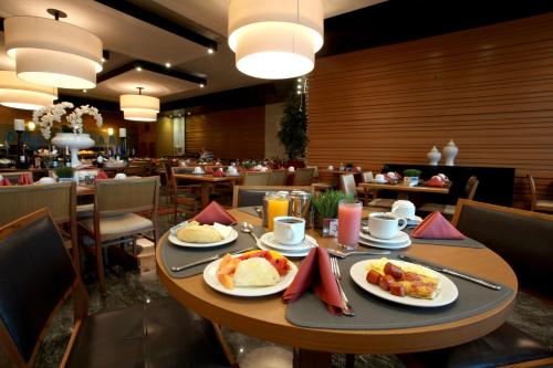 Royal Macaé Palace Hotel في ماكاي: طاولة عليها أطباق من الطعام في مطعم