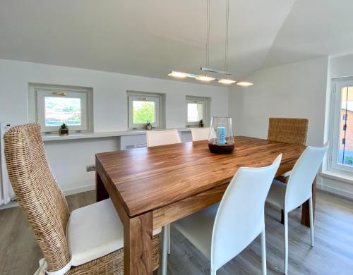a dining room with a wooden table and white chairs at ABIES lago di Como in Dongo