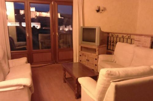 sala de estar con 2 sillas blancas y TV en CASA RURAL ALTA YUBERIA en Berlanga de Duero