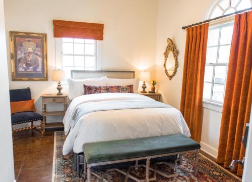 a bedroom with a bed and a chair and windows at Armory Park Inn in Tucson