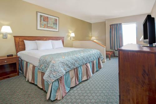 a hotel room with a bed and a flat screen tv at Days Inn by Wyndham Downtown St. Louis in Saint Louis