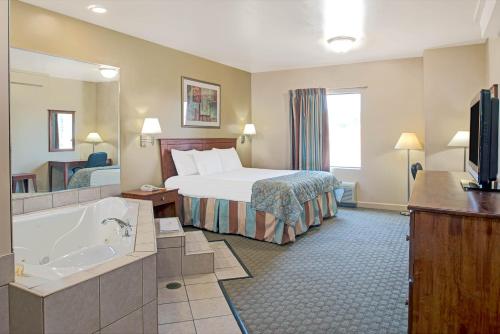 a hotel room with a bed and a bath tub at Days Inn by Wyndham Downtown St. Louis in Saint Louis