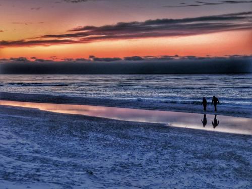 two people walking on the beach at sunset at Mistral przy plaży Domki całoroczne in Ustka